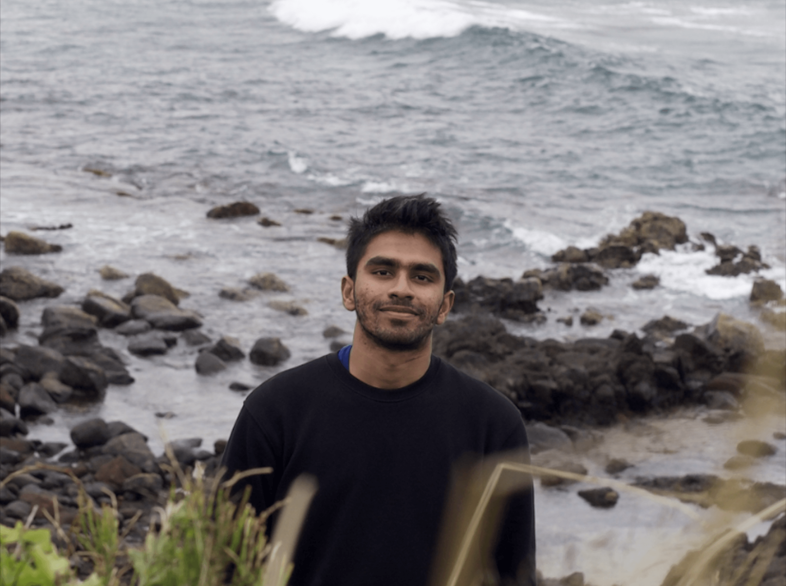 Thenuja standing by a rocky coastline